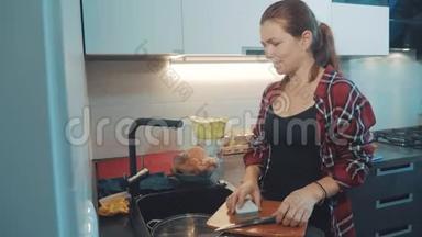 女孩在厨房砧板上洗碗。 女人在厨房做饭。 女孩在水槽下面洗了一把刀